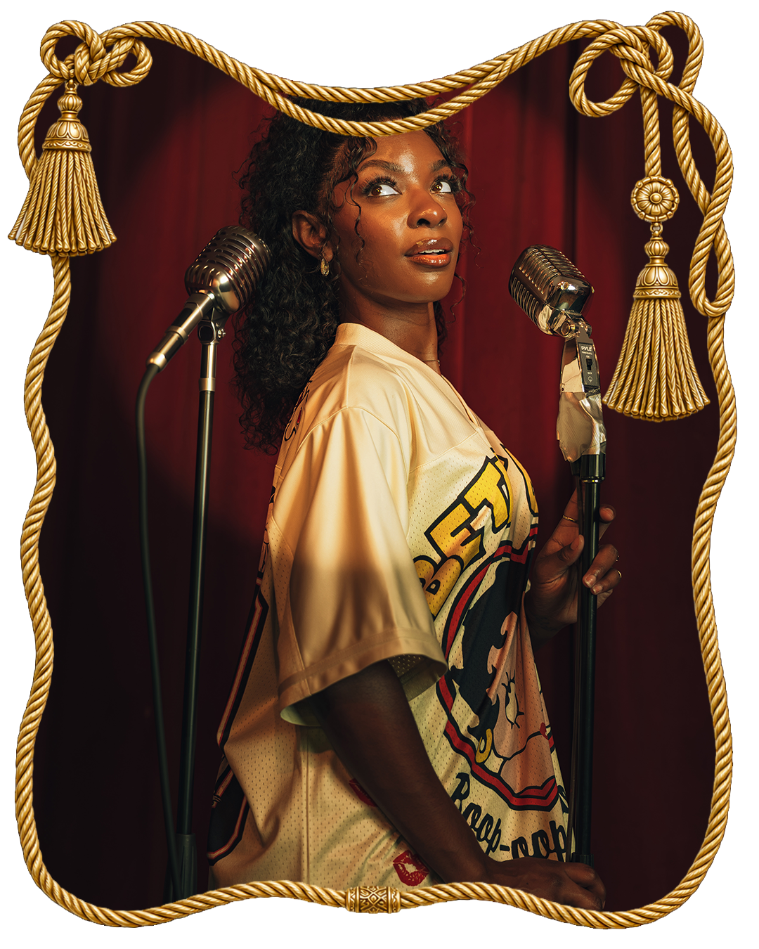 Woman in a vintage shirt stands by microphones against a red curtain backdrop.