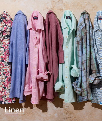 A collection of linen shirts in various colors and patterns hanging.