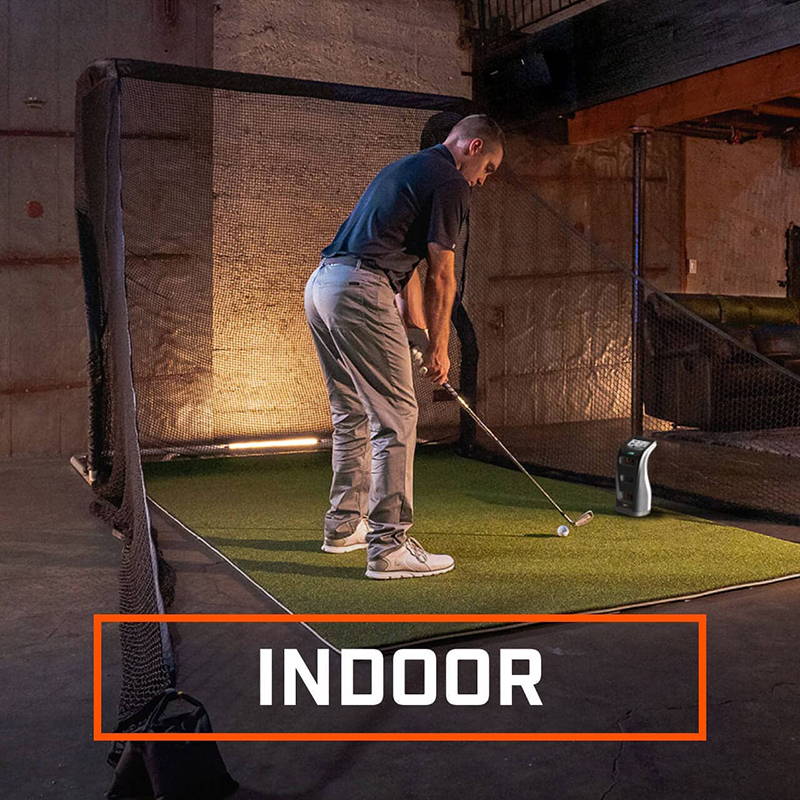 A golfer using the Bushnell Launch Pro indoors with a golf mat and golf hitting net