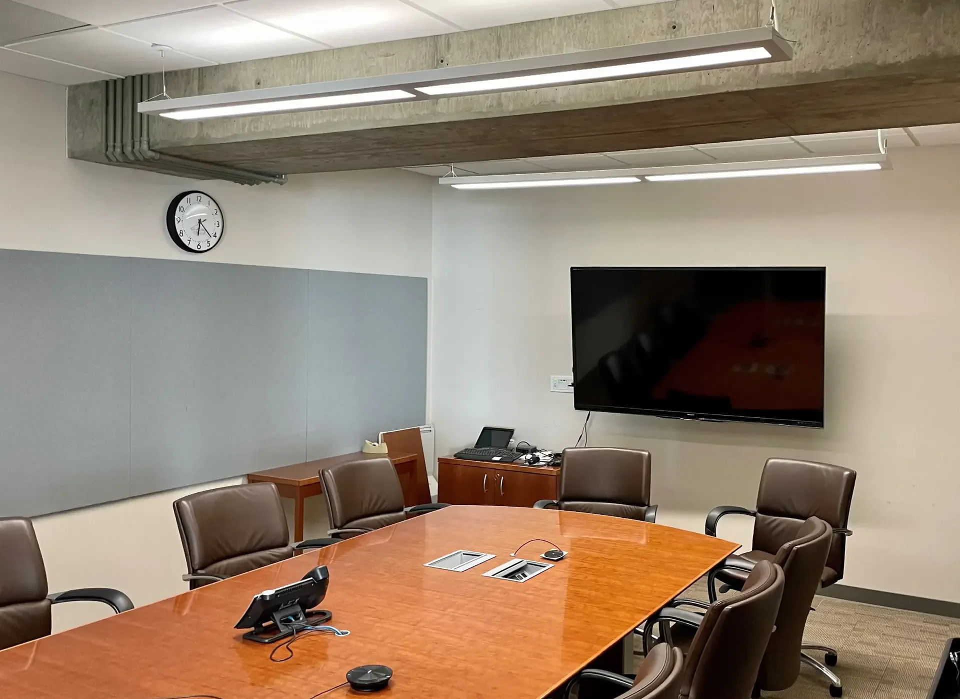 A modern conference room with a large table and wall-mounted screen.