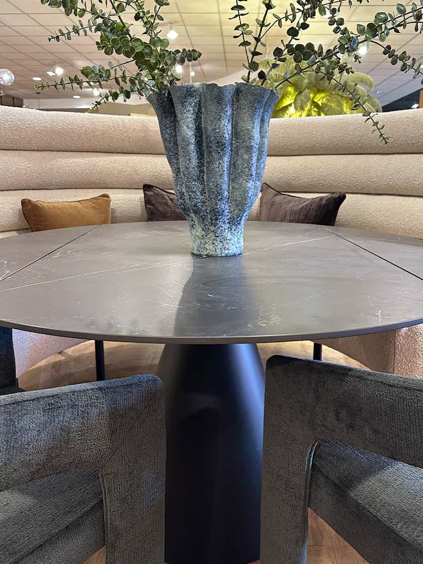 Round black stone table and curved boucle dining bench