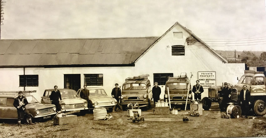 Group of people and vintage cars outside a building.