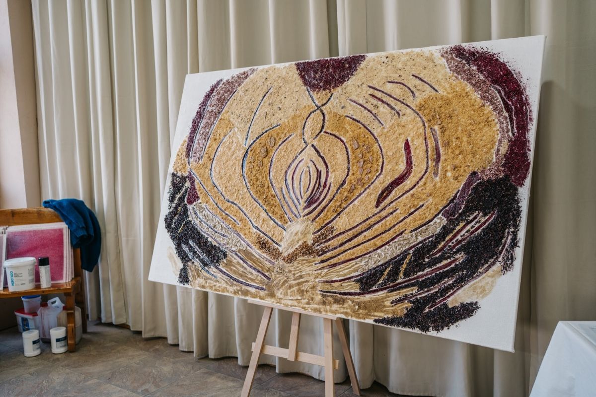 Abstract artwork displayed on an easel against a curtain backdrop.