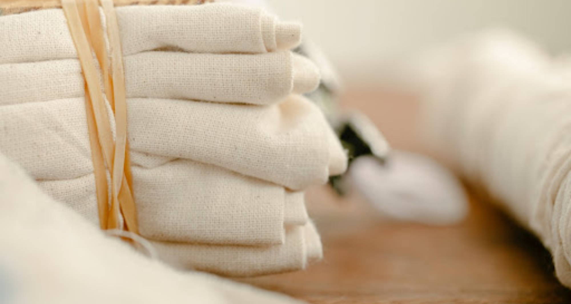 A pile of white hemp fabric sits bound by a ribbon on a table.