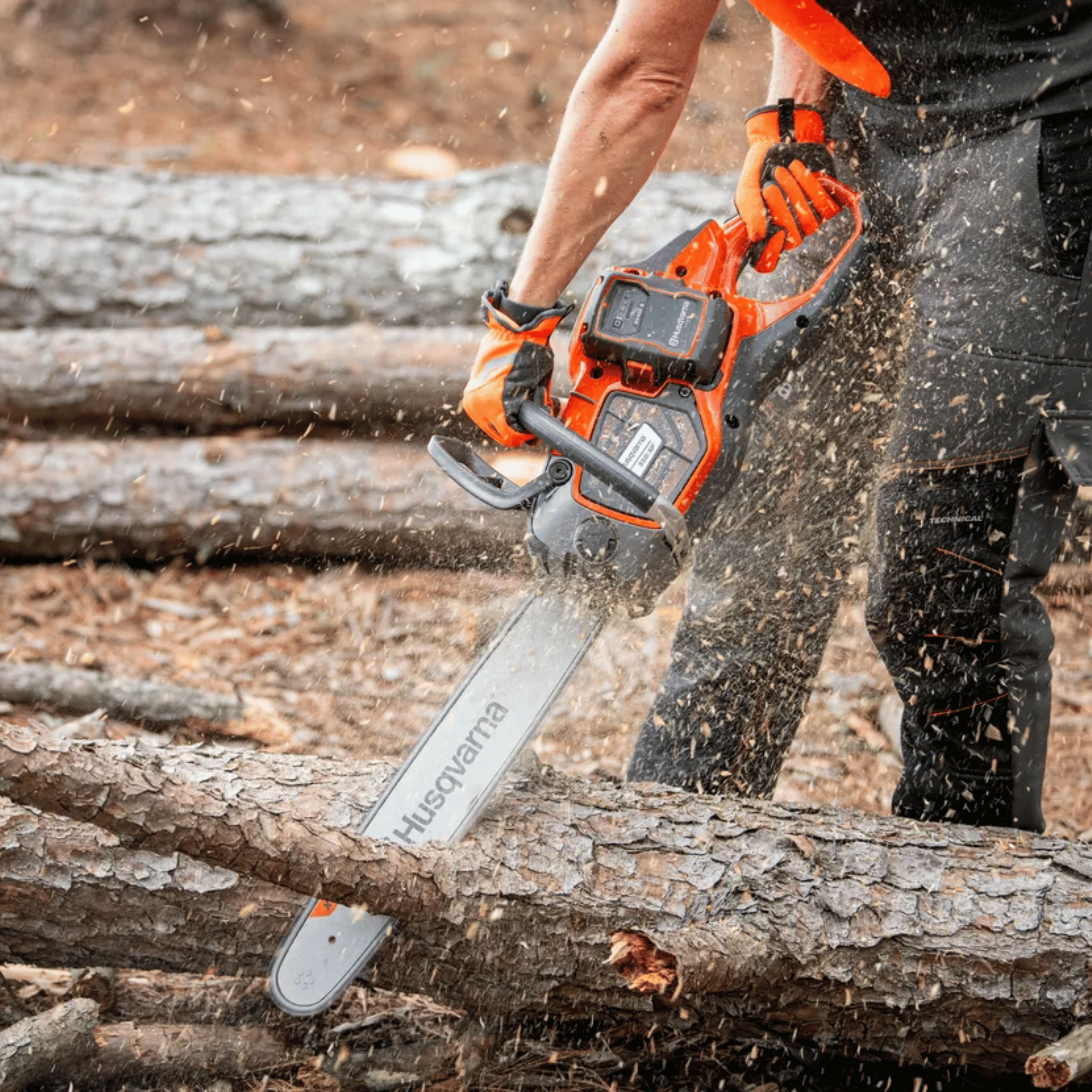 Person using a chainsaw to cut logs in a wooded area.