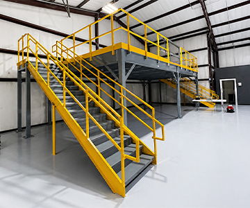 Metal staircase with yellow railings in an industrial space.