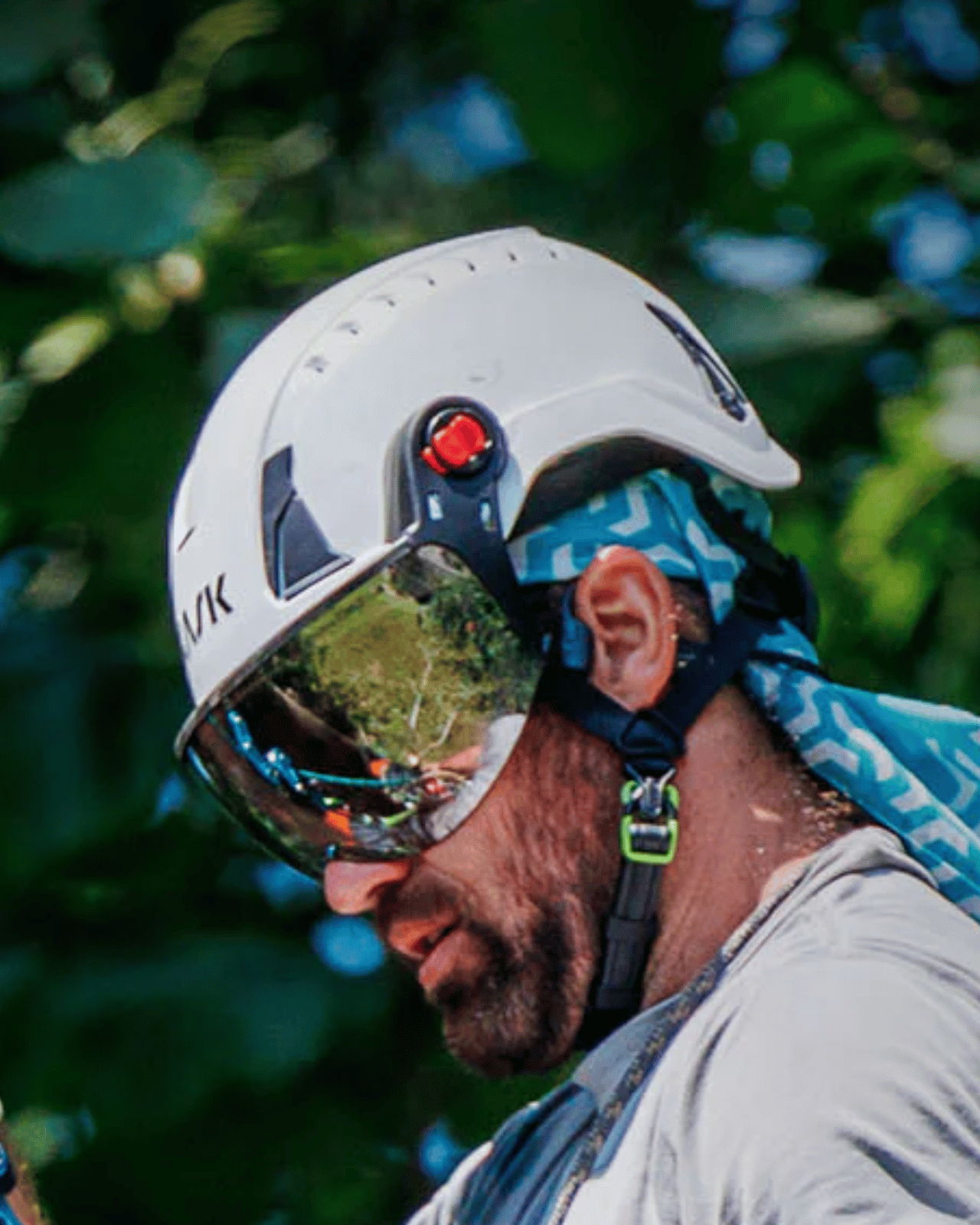 Person wearing a helmet and goggles, surrounded by green foliage.