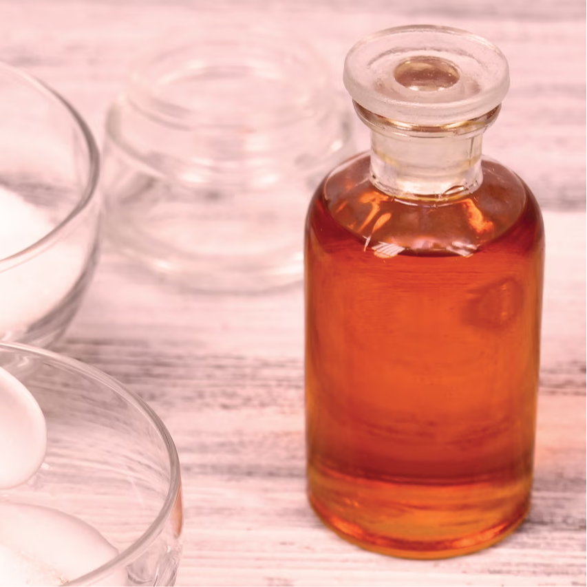 Bottles and bowls with sugar and a liquid ingredient on a wooden surface.