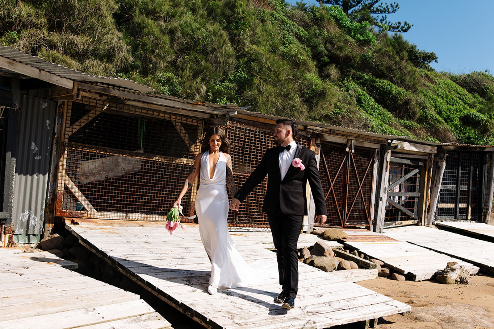 Bride and groom walking hand in hand on a sunny day.