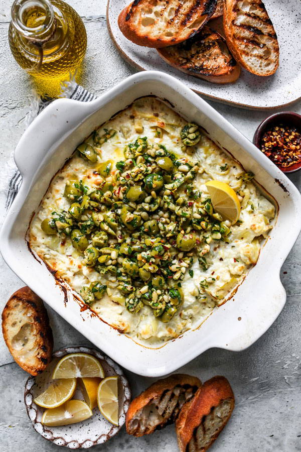 Melty baked Feta cheese dip with artichokes. Topped with an herbaceous olive gremolata
