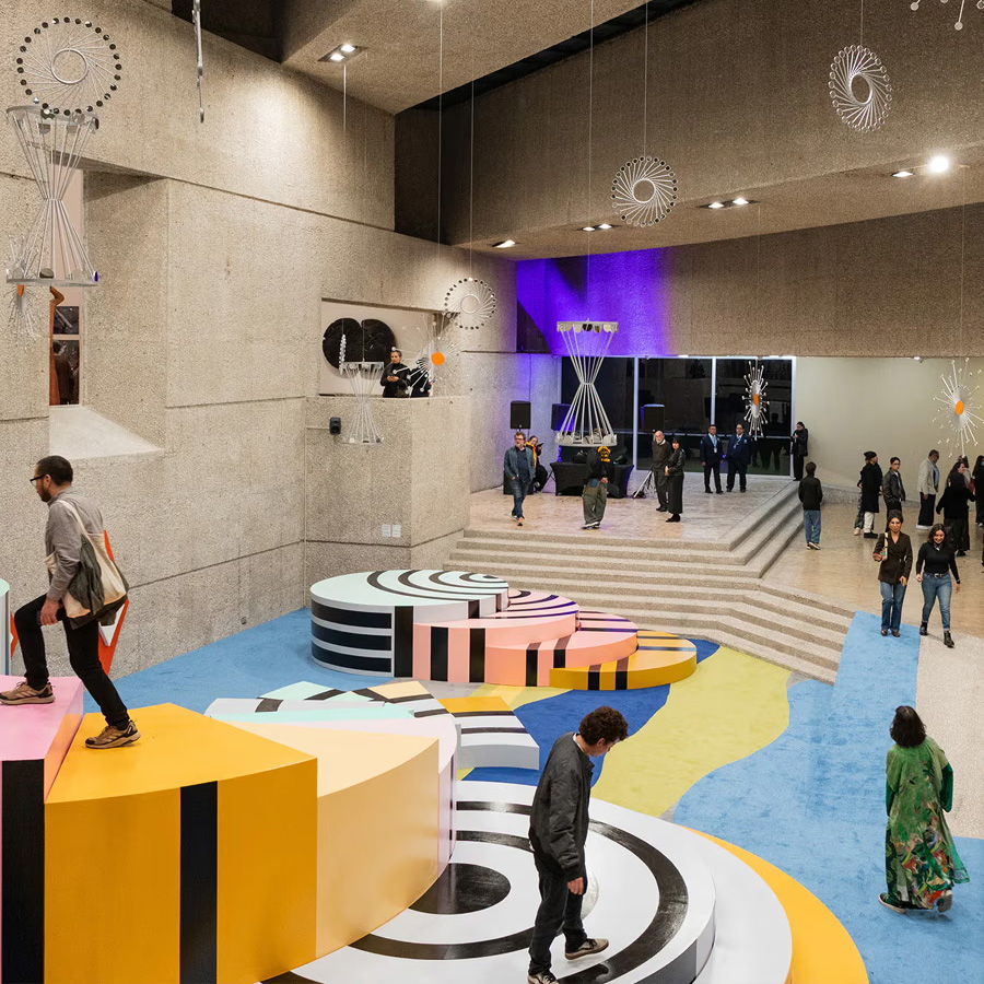 Modern art installation with colorful geometric platforms and people interacting in a gallery.