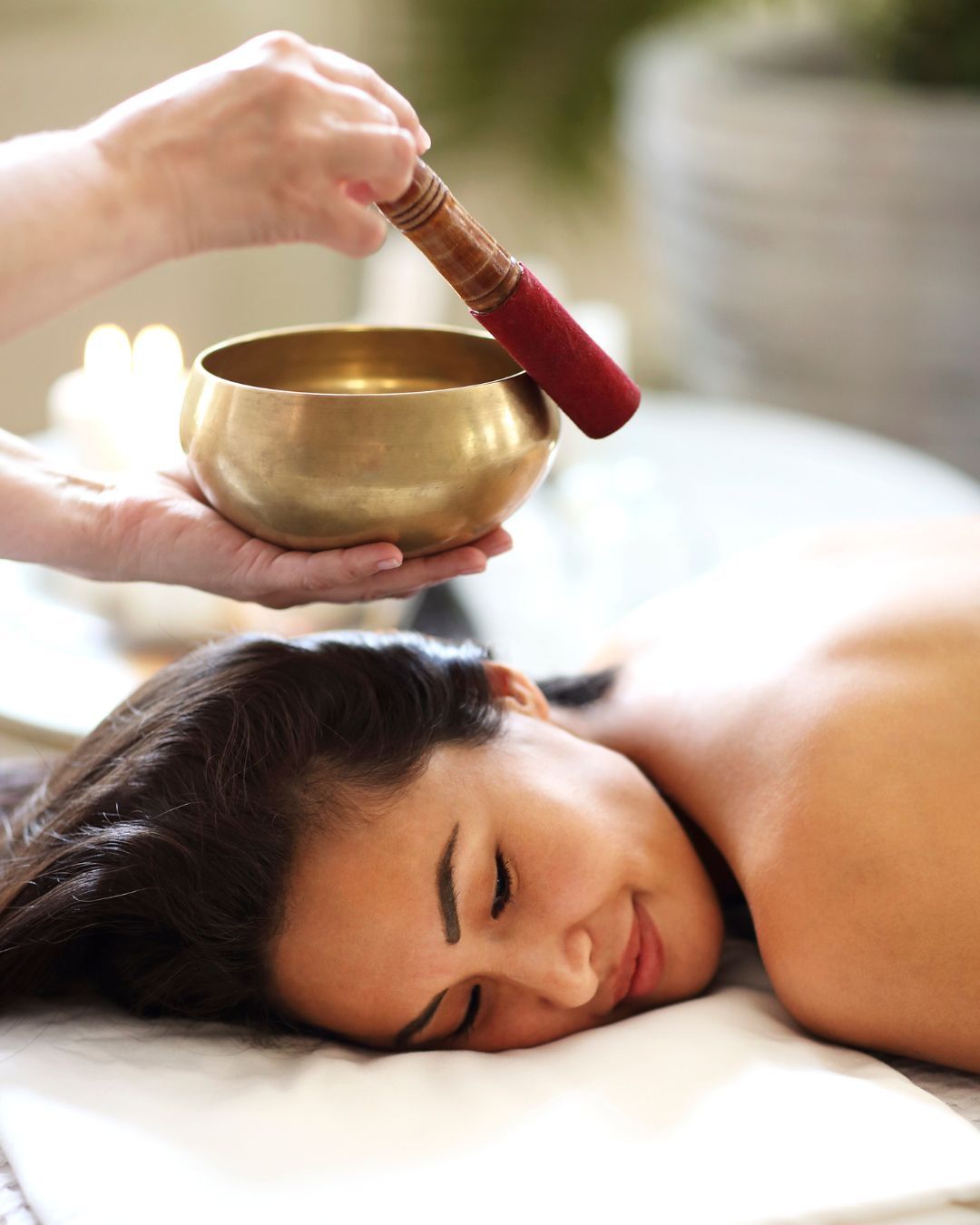 A woman receiving a sound therapy treatment with a singing bowl.