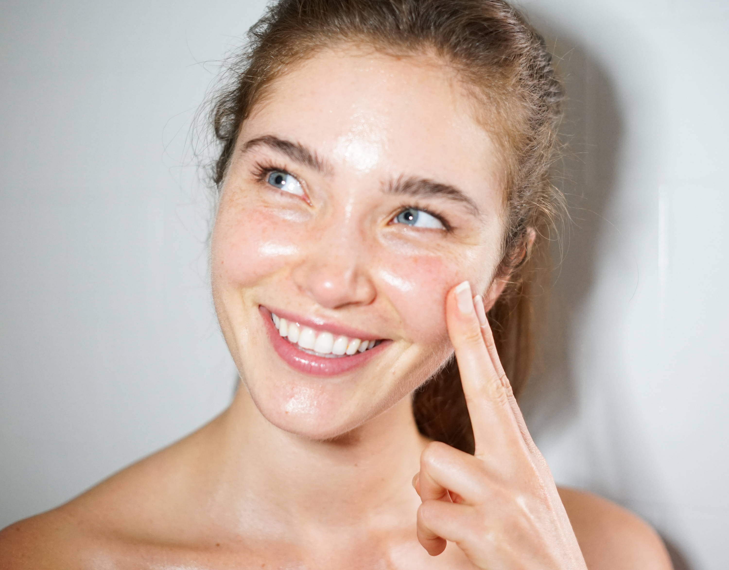 A woman smiling while feeling her cheek with her fingers