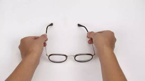 Mains tenant des branches de lunettes en métal noir pour les serrer pour empêcher les lunettes de glisser de votre nez