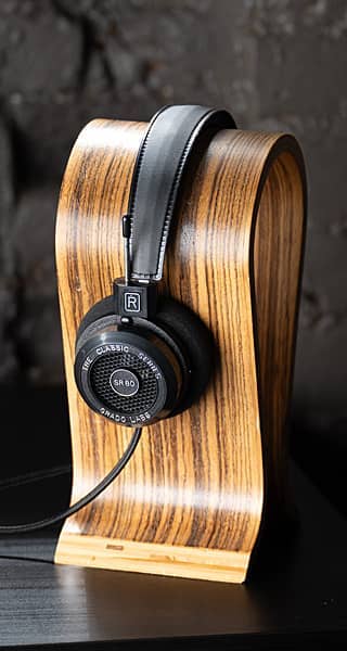 Headphones resting on a stylish wooden stand against a dark background.