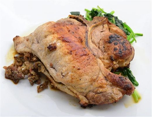 Roasted meat dish served with sautéed greens on a white plate.