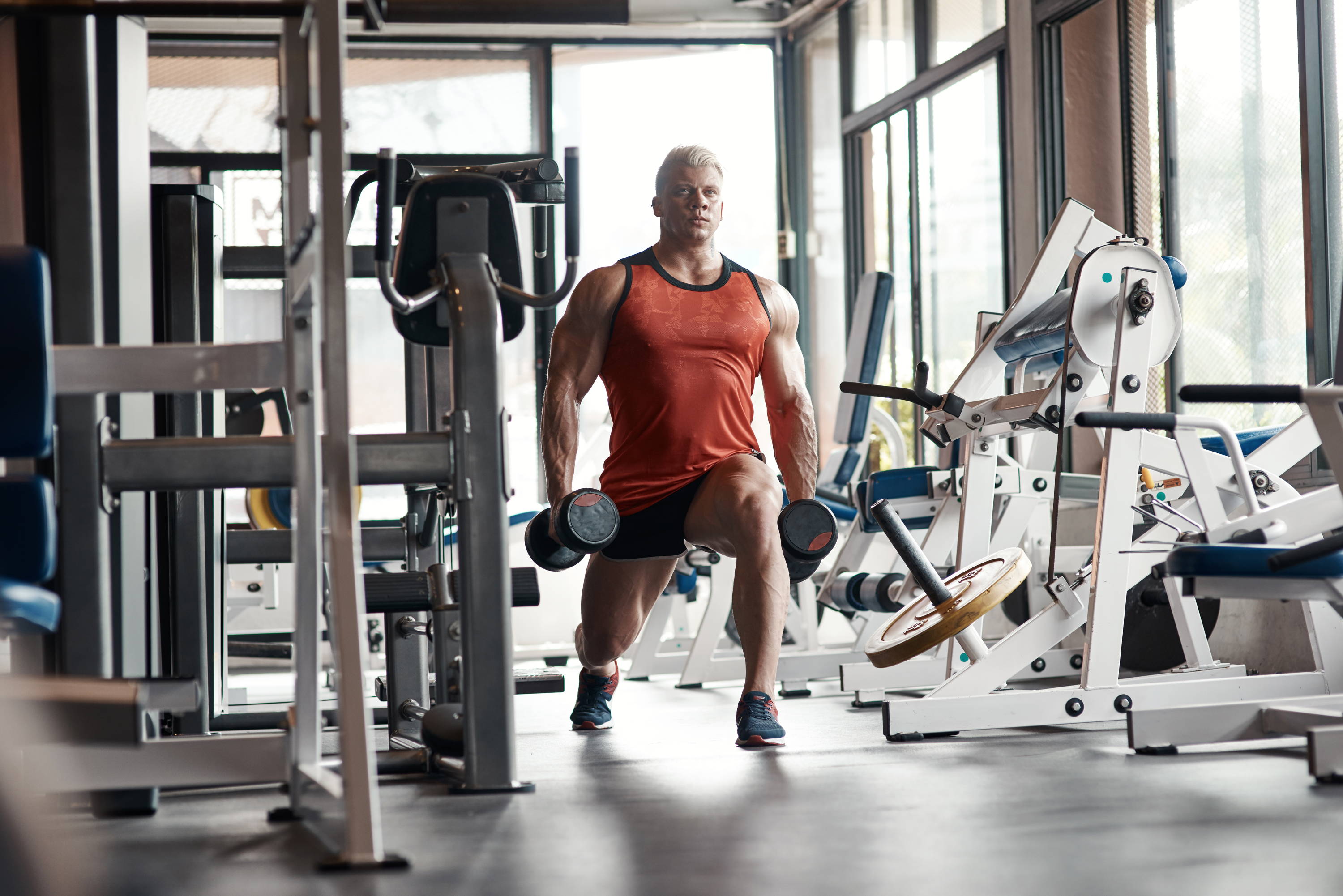 Man in red singlet training with dumbbells