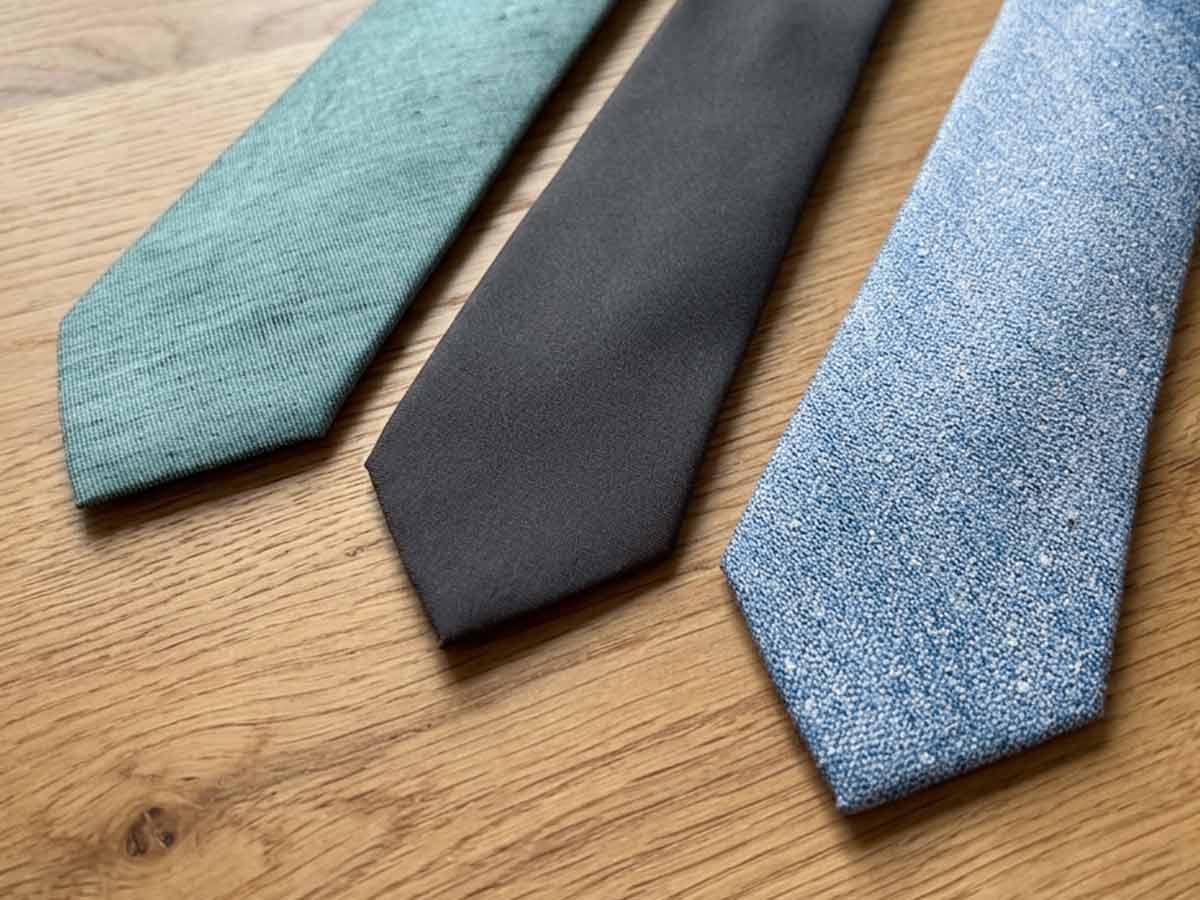 Flat lay of three simple textured ties on a wood background