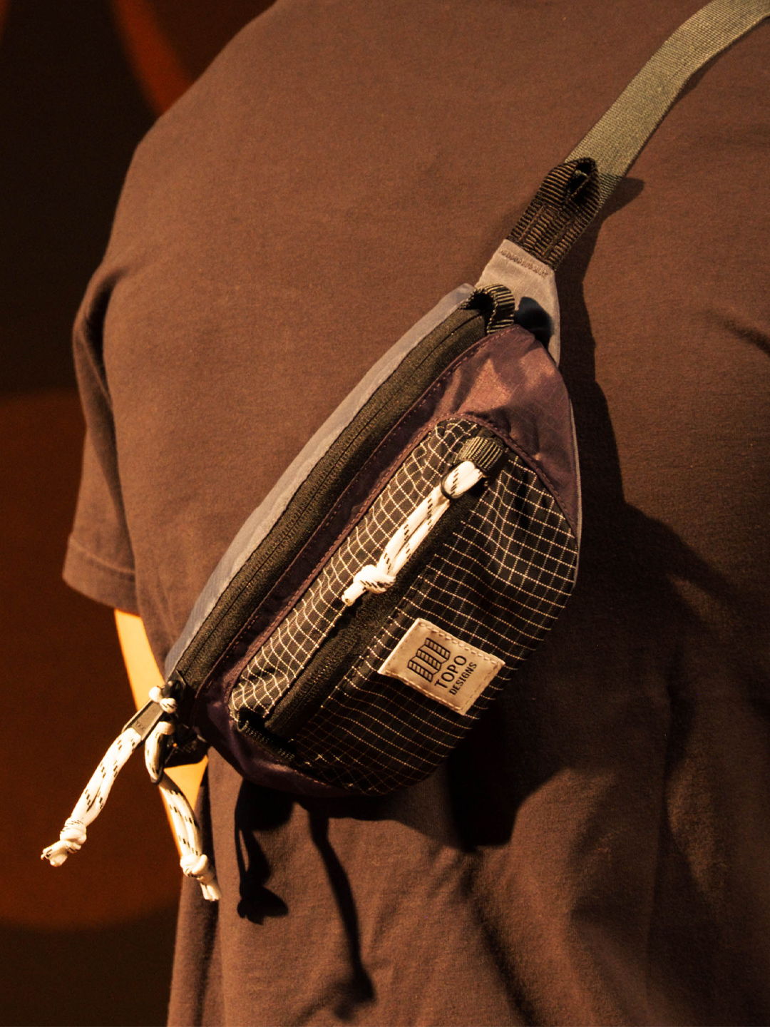 A person wearing a black and gray sling bag.