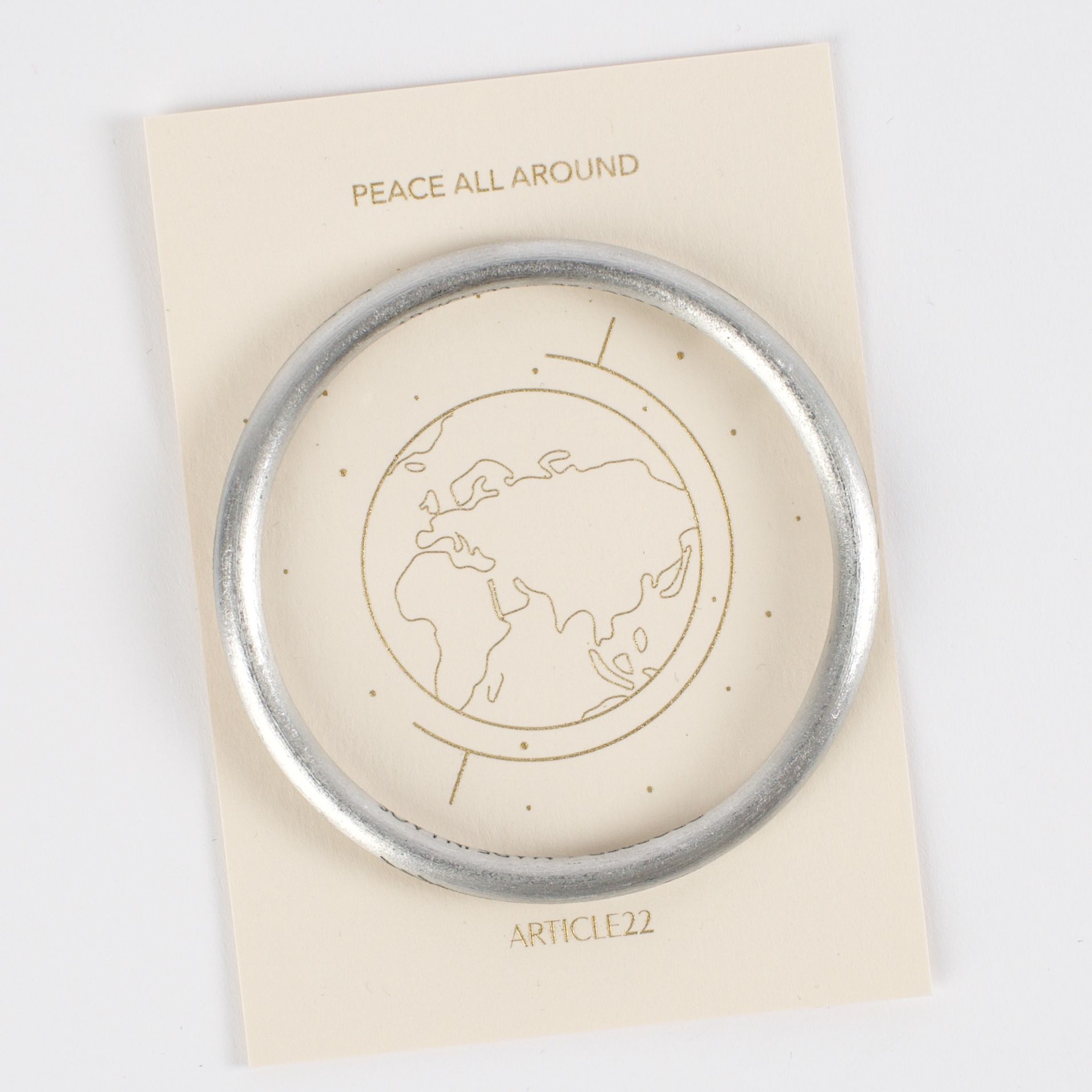 A silver bangle on a card with a world map design.