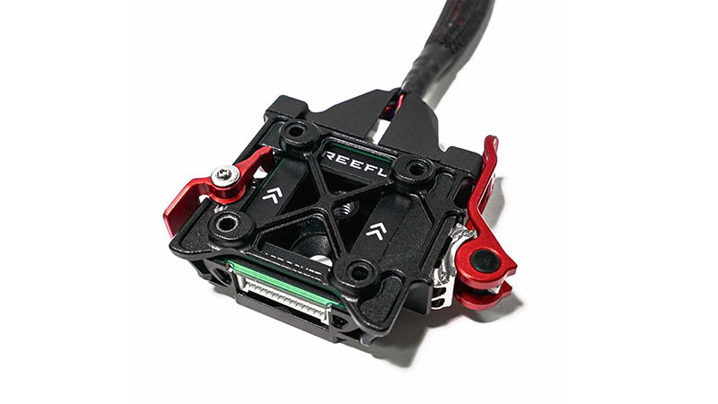 Mechanical component with black and red parts, featuring a connector and wiring.