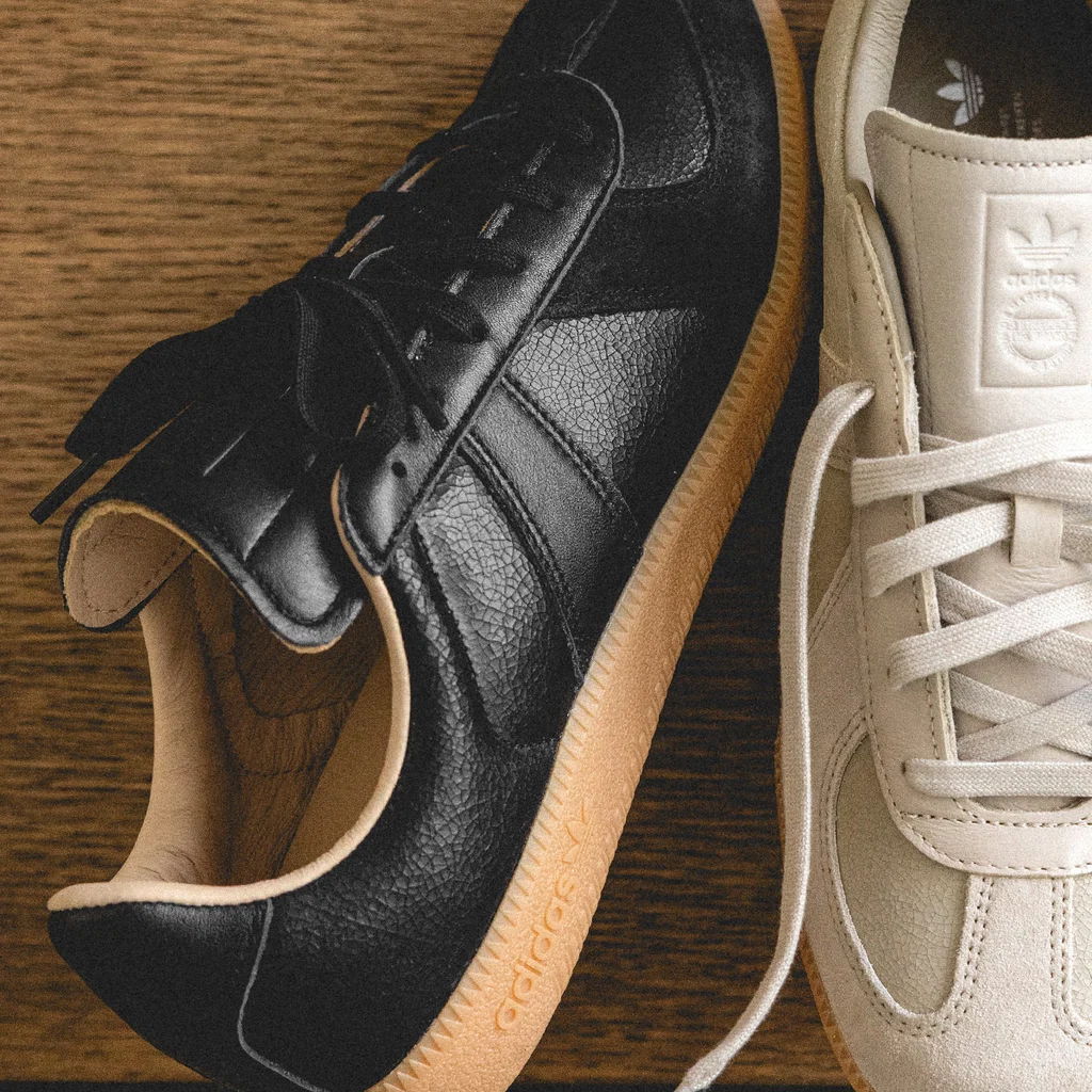 A pair of sneakers, one black and one white, on a wooden surface.