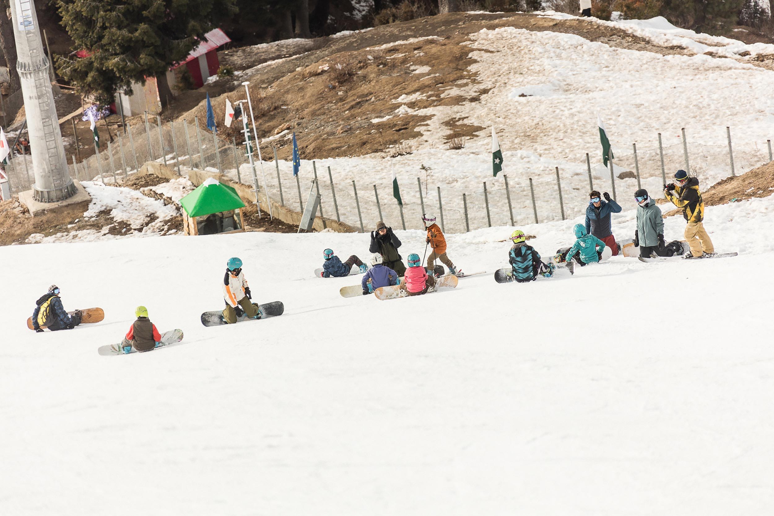 People snowboarding and resting on a snowy slope.