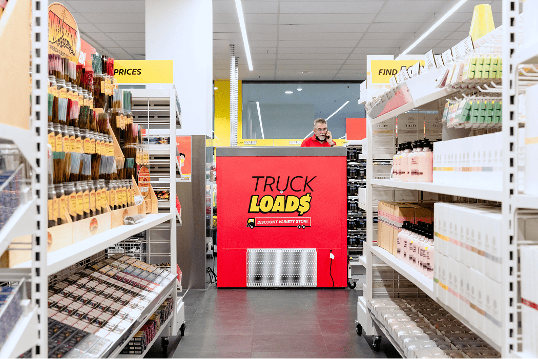 A store aisle with shelves and a red display sign reading 