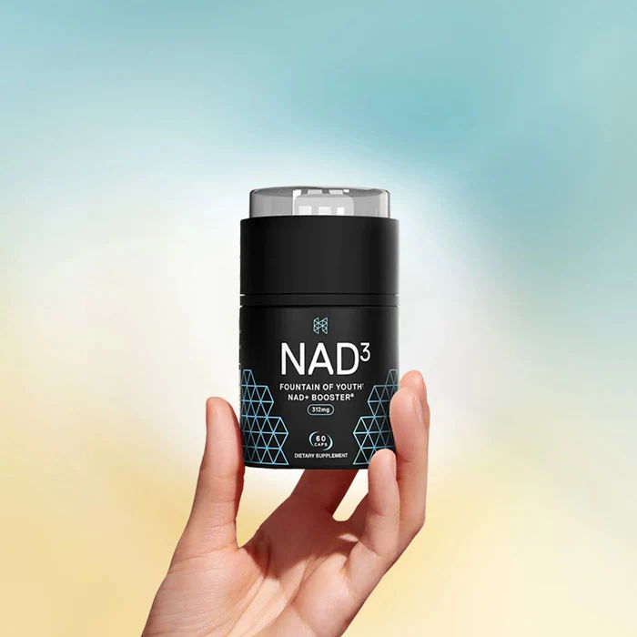 Mano sosteniendo un producto para el cuidado de la piel de color negro sobre un fondo borroso.