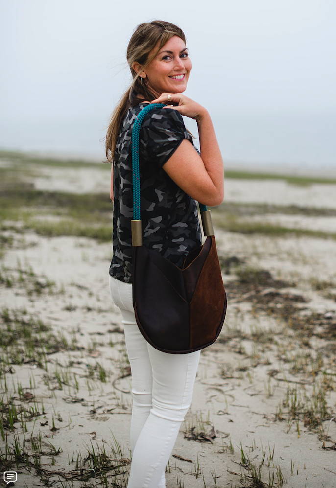 woman smiling while holding bag on the beach