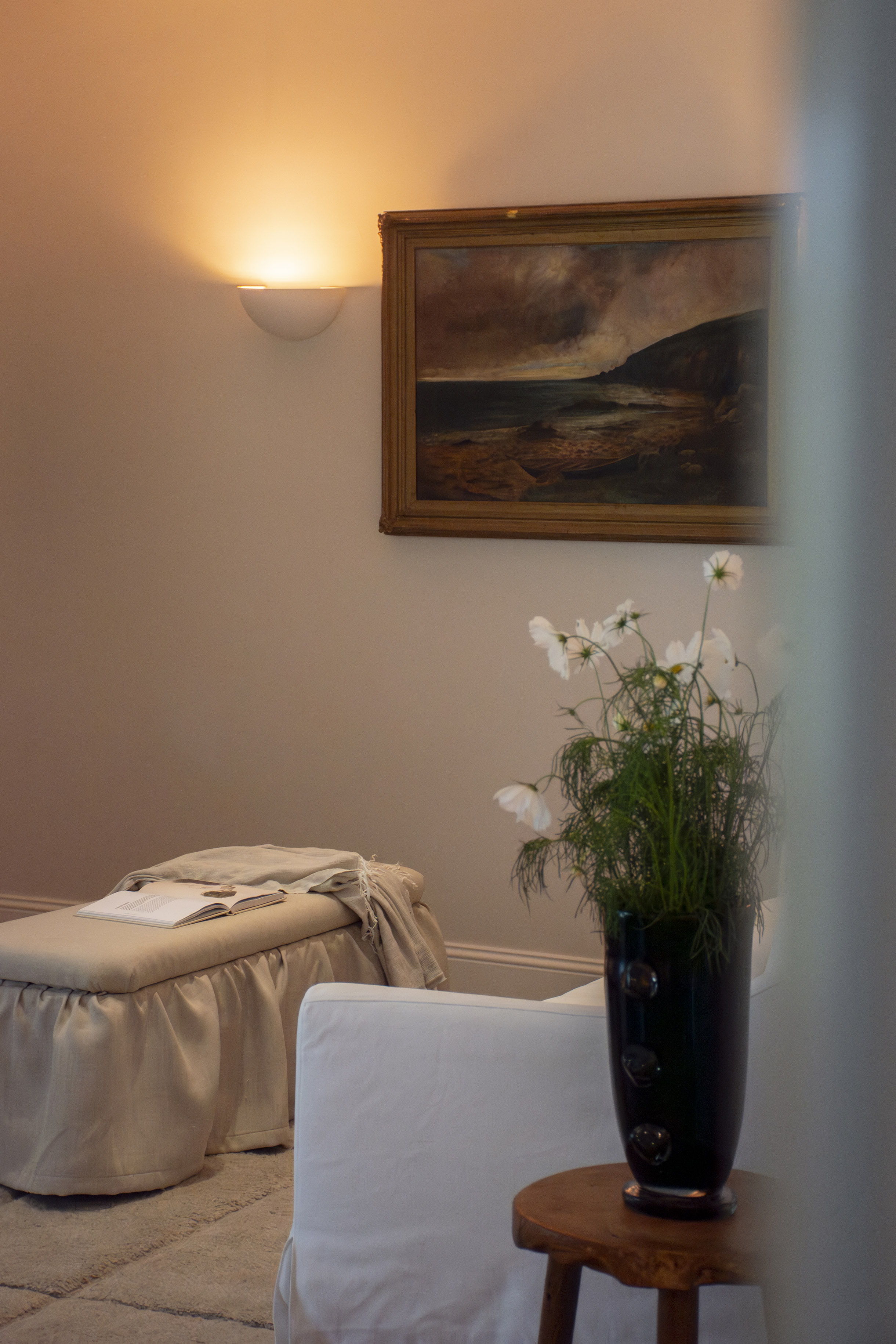 Cozy room with a painting, flowers, and soft lighting.