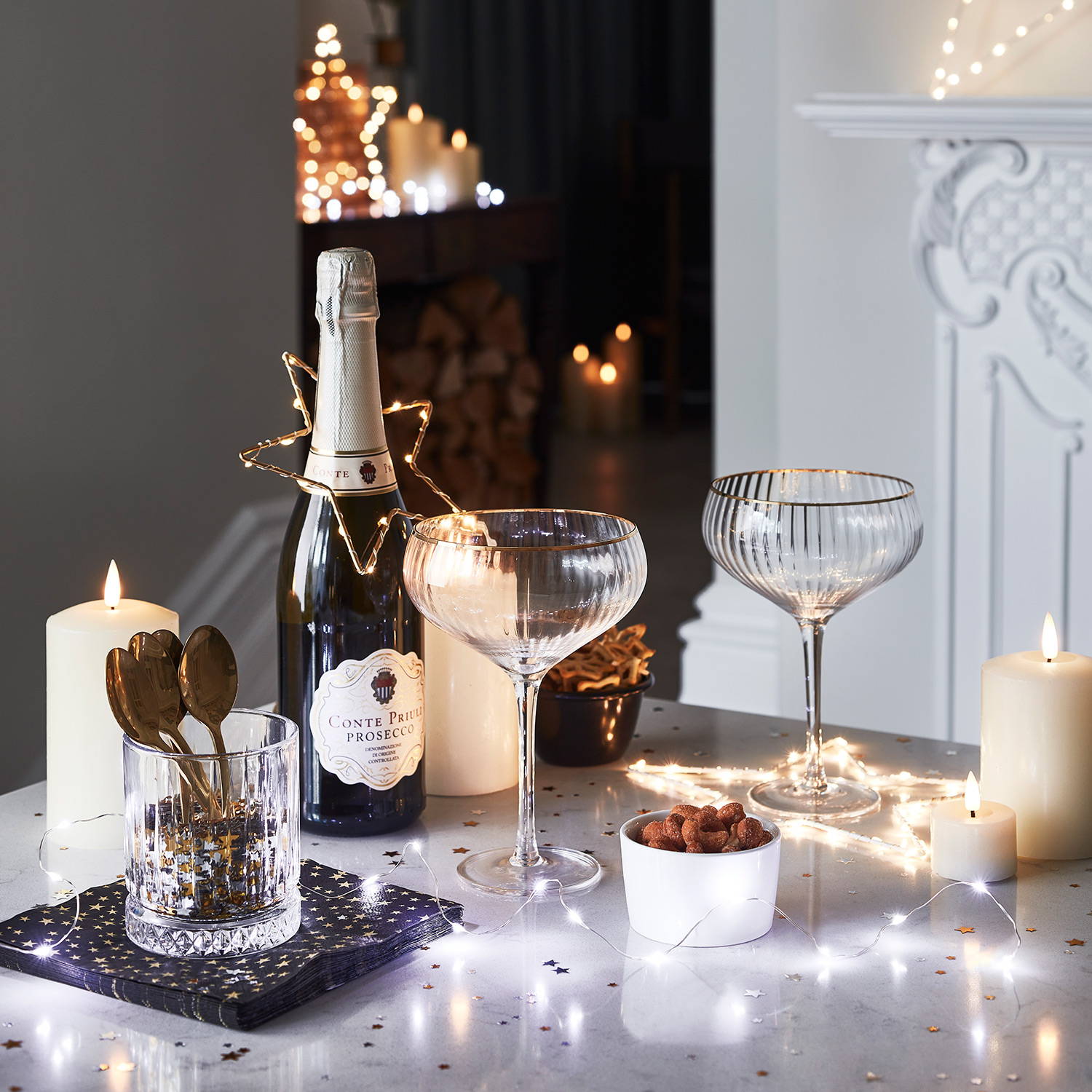 Table with prosecco, glasses, LED candles, star lights and fairy lights.