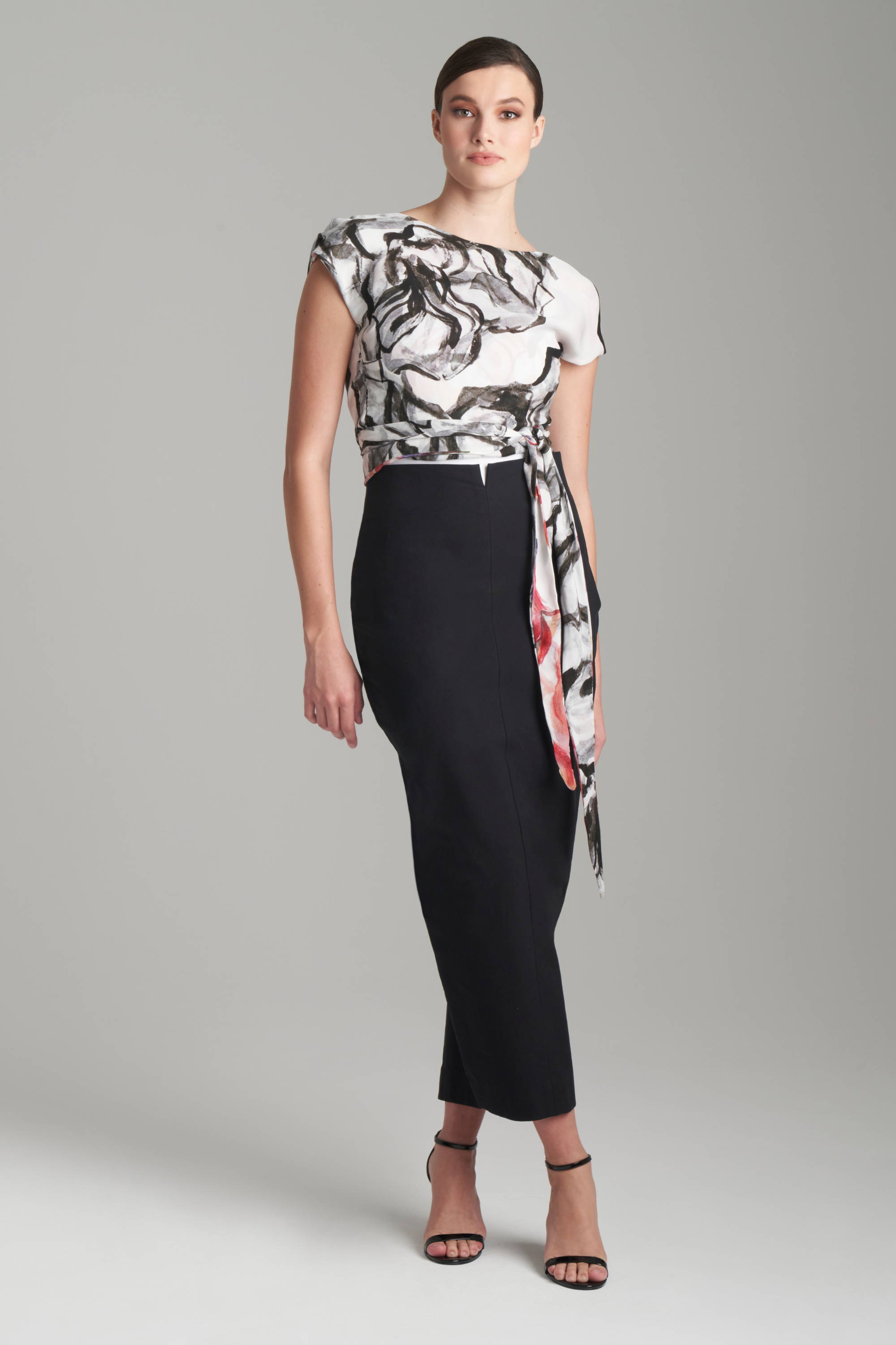 Woman wearing black and white rose prnted silk reversible wrap top with cotton black pencil skirt by Ala von Auersperg