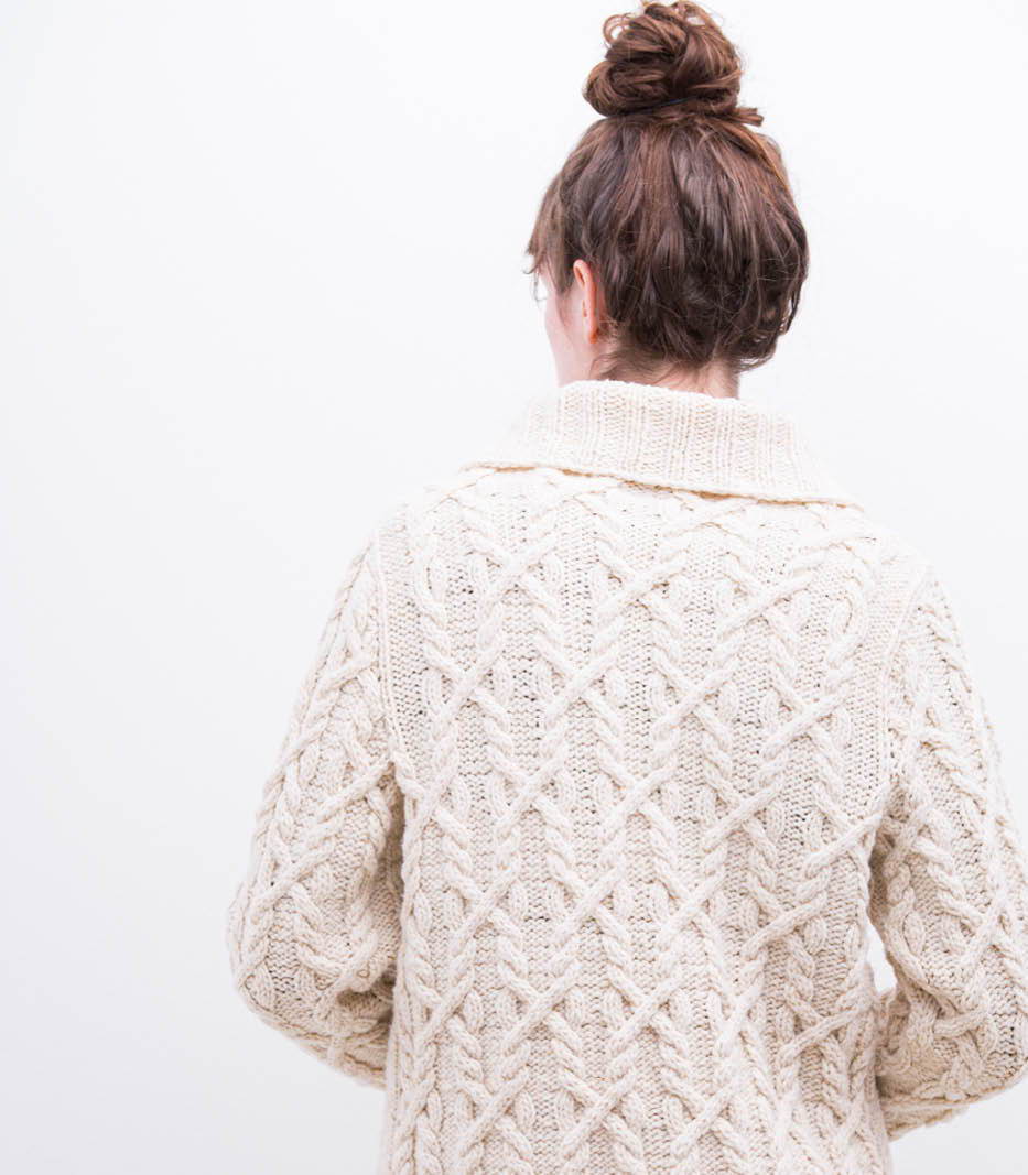 Back view of a female model wearing a hand knit all-over cable cardigan.