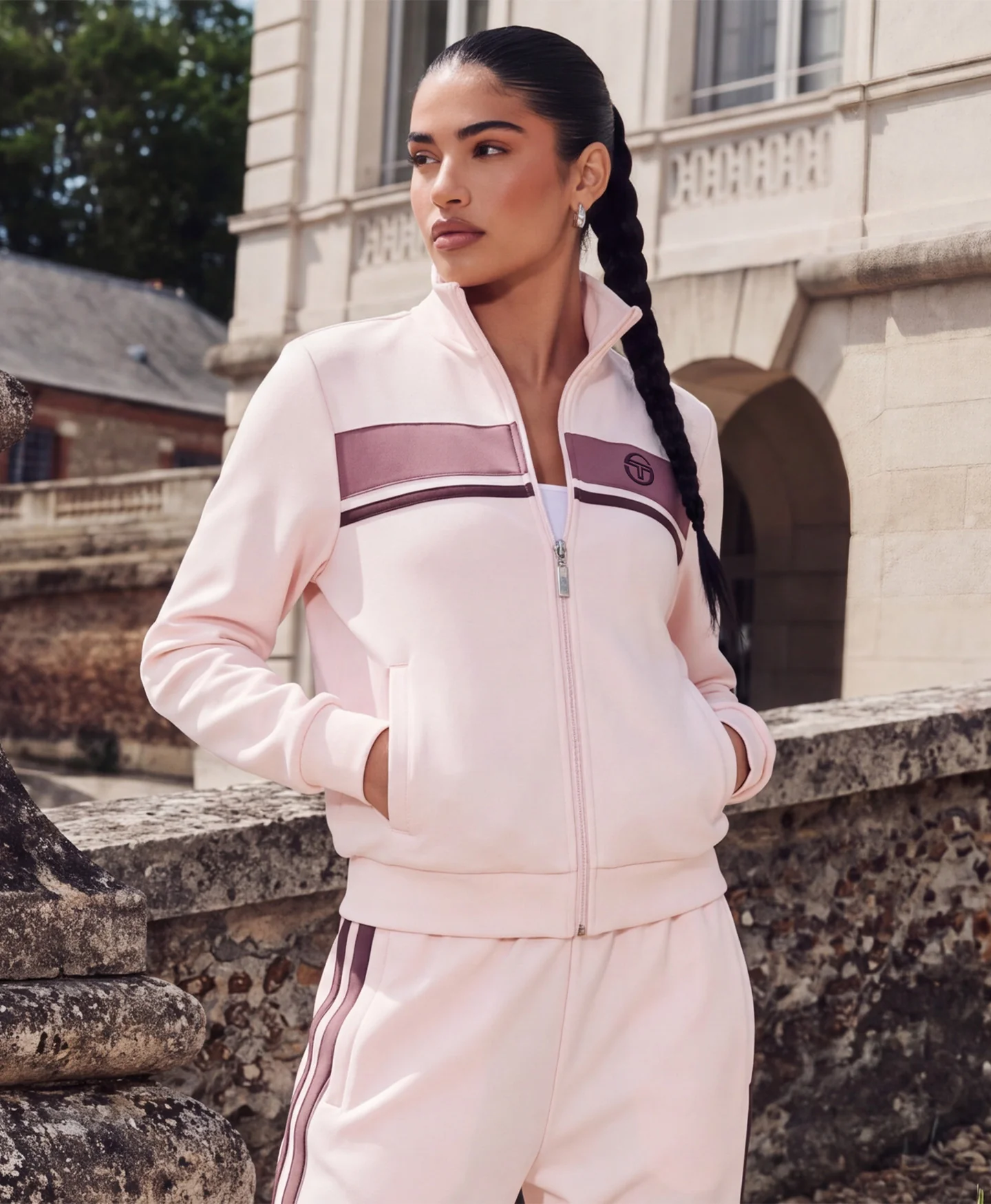 Young woman in pink athletic Sergio Tacchini outfit standing outdoors.