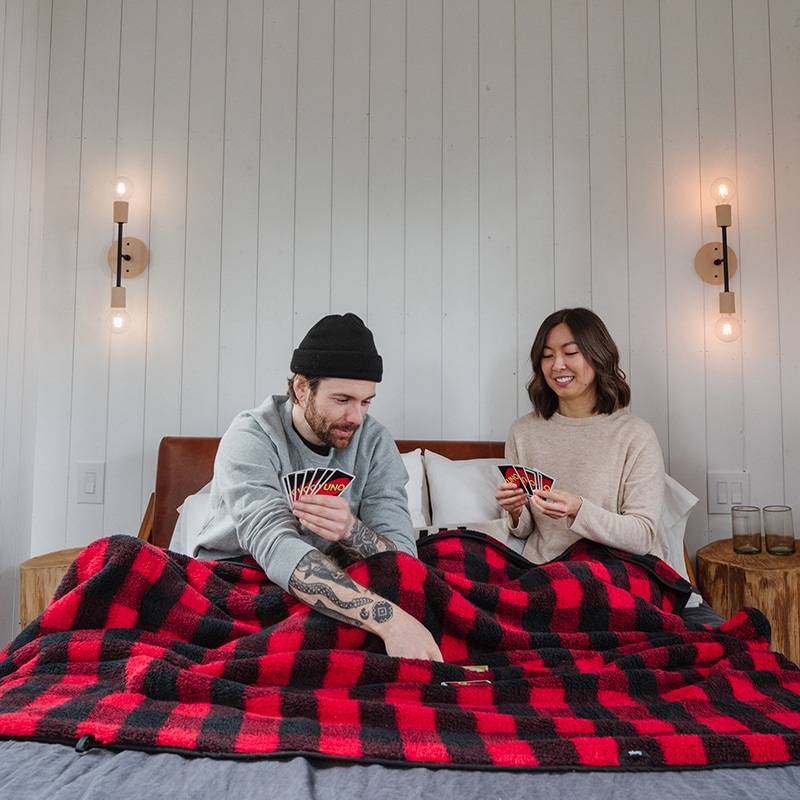 Couple sitting on bed under Sherpa Fleece Blanket playing cards