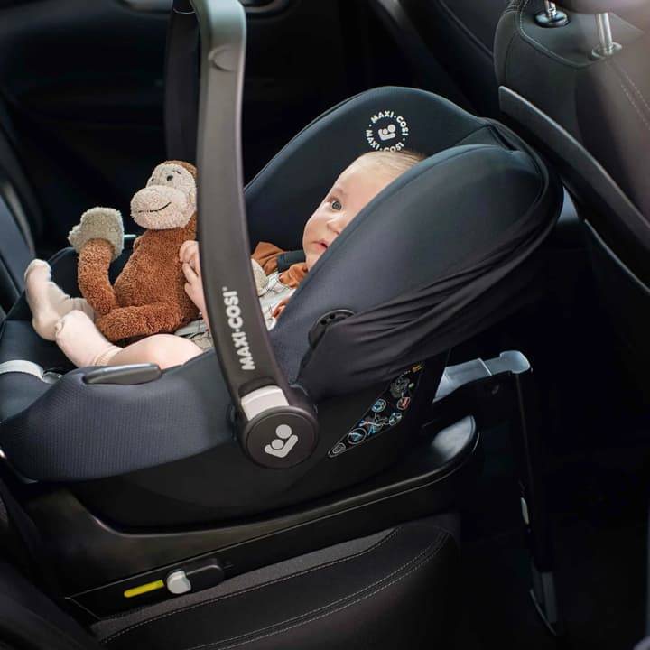 Baby in a Maxi-Cosi car seat with toy monkey