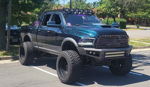 Front three-quarter view of lifted teal Ram pickup with custom bumper, LED lights, and Mandalorian grille