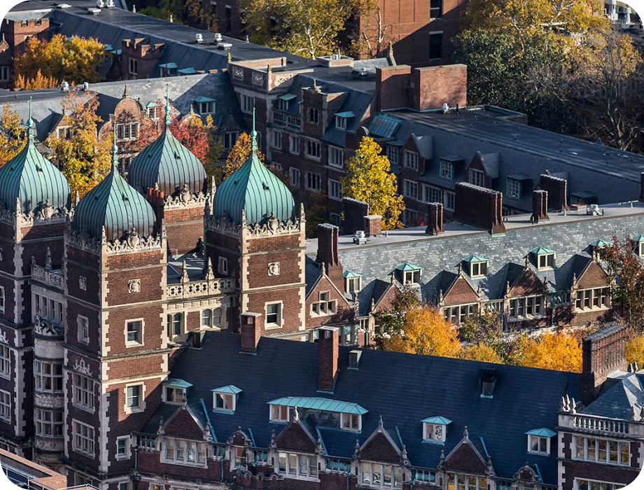 Aerial view of historic buildings surrounded by autumn foliage.