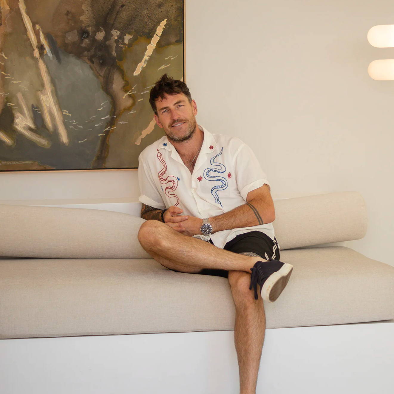 Artist Stephen Skinner sitting on a sofa at Lighting Collective's showroom.