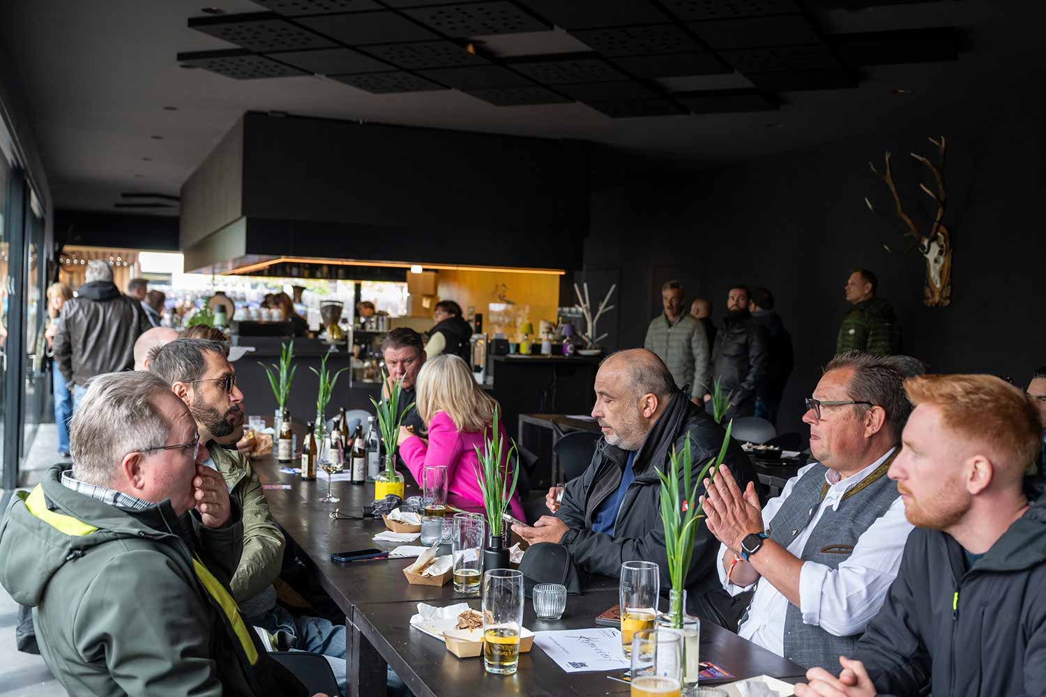 Group of people dining at a restaurant with drinks and flowers on the table.