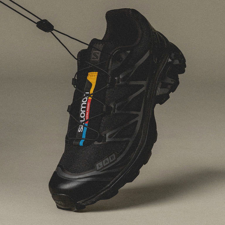 A black athletic shoe suspended against a neutral background.