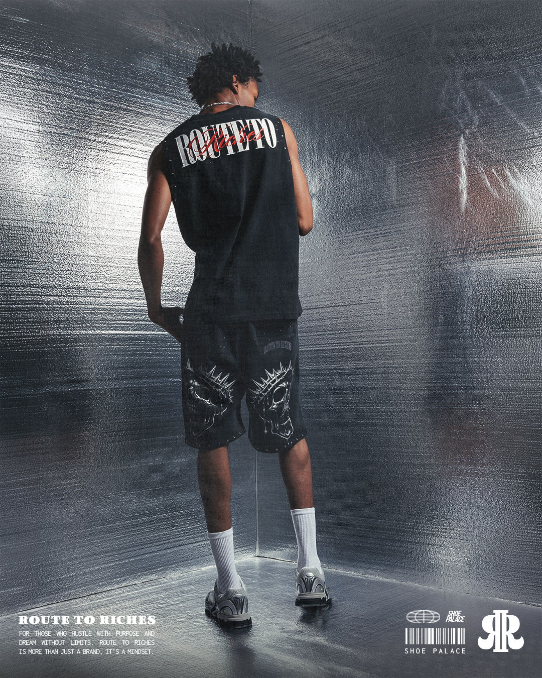 Person wearing a sleeveless shirt and shorts, standing against a reflective background.