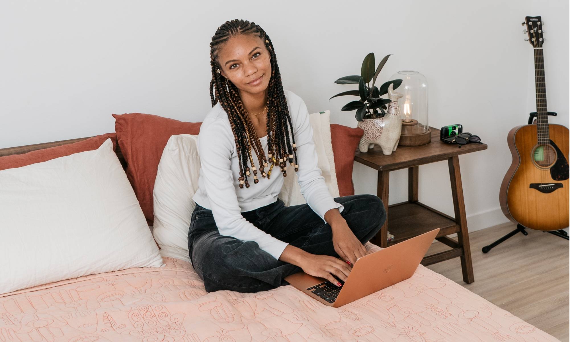 Leah Thomas working on computer in platform bed with wood side table