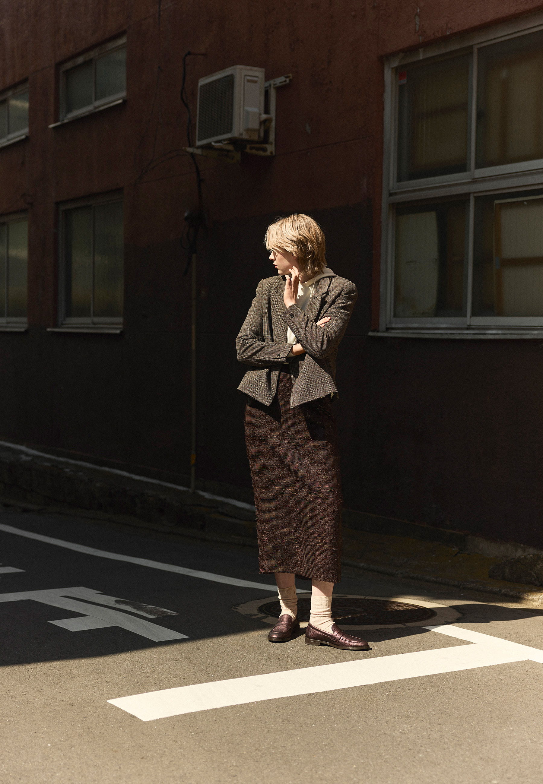 Person in a suit standing on a street with buildings in the background.