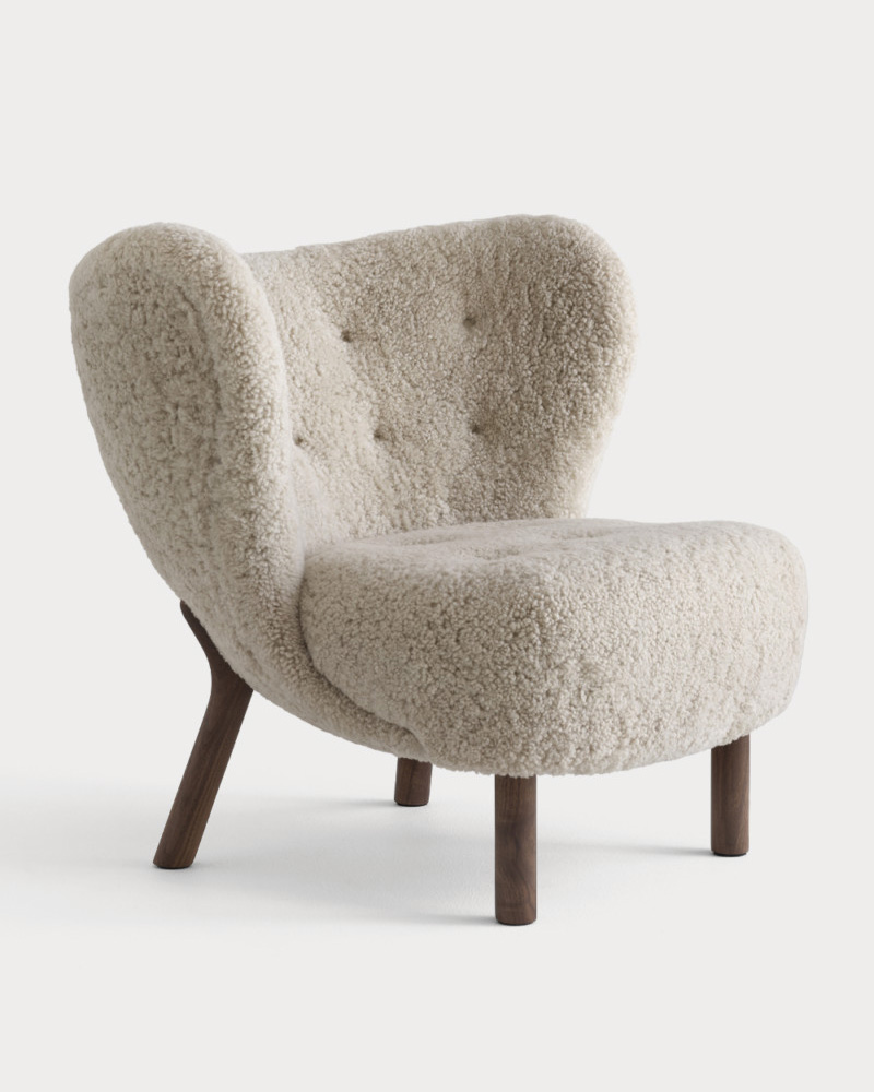 A cozy, textured &Tradition armchair with wooden legs and button details.