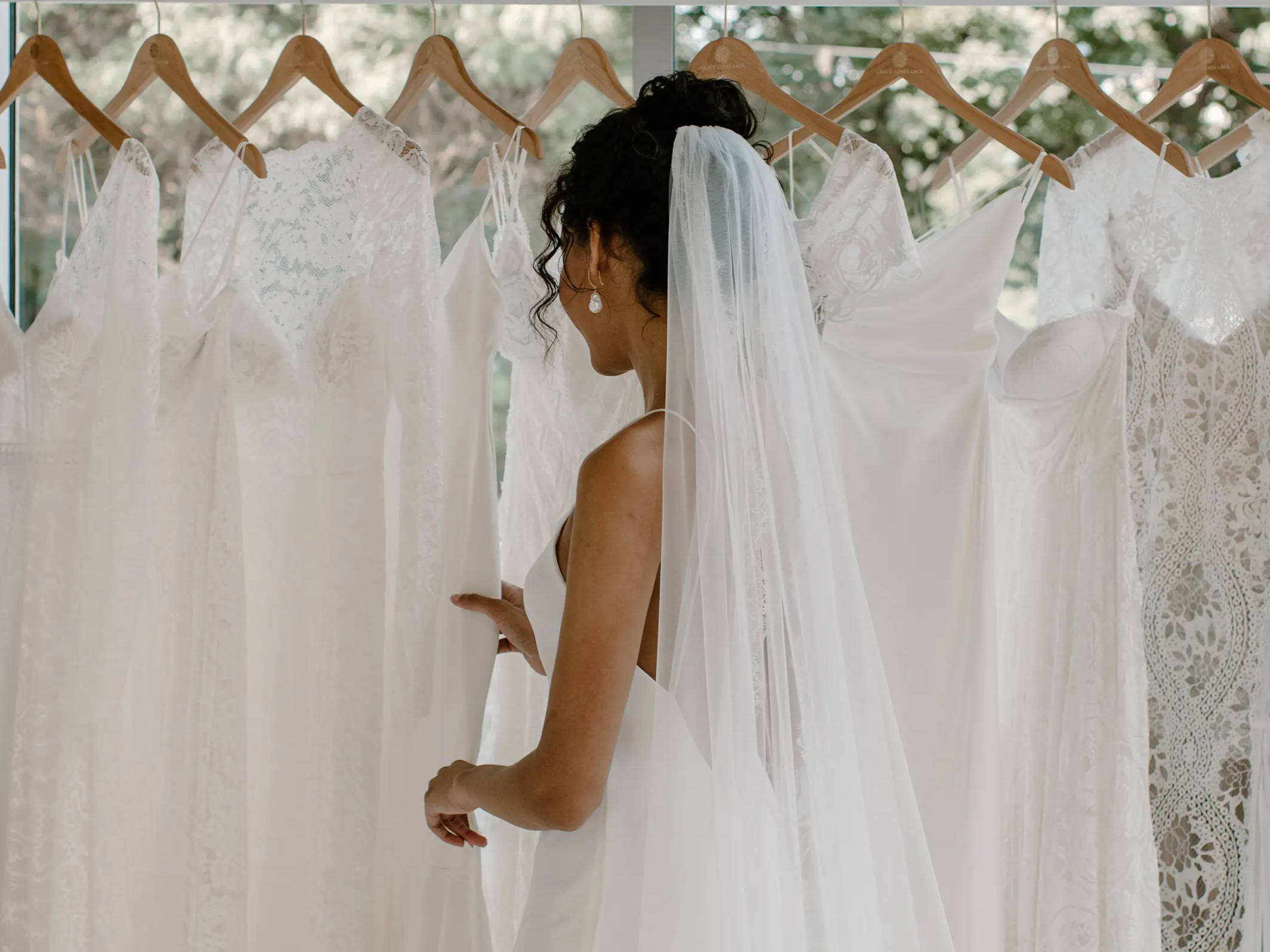 Bride looking through Grace Loves Lace dresses wearing the Henri veil