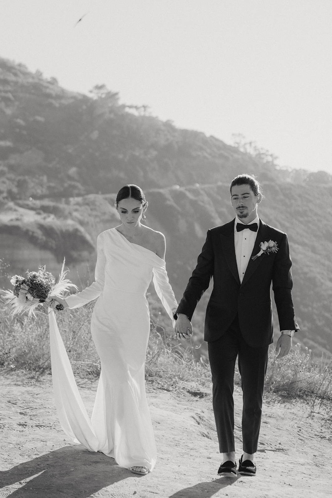 Bride and groom walking together with a coastal background