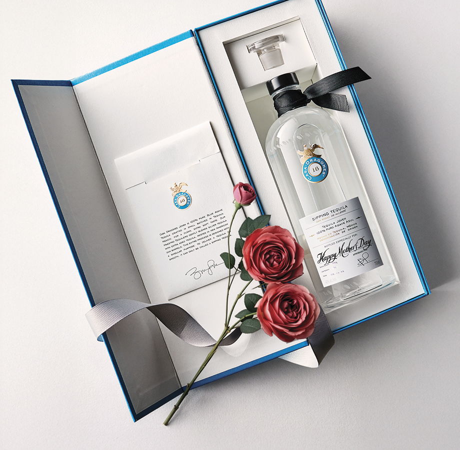 Gift box containing a bottle and card, adorned with red roses.