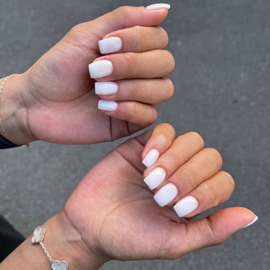 Two hands showing manicured white nails.